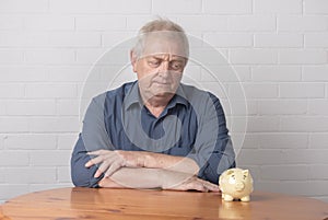 Mature man looking at a piggy bank