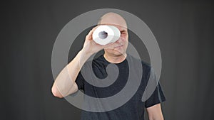 Mature man looking through tissue paper roll