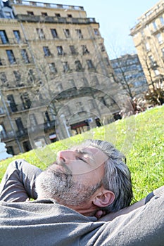 Mature man lying in grass in citytown photo