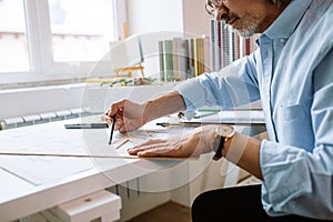 Mature man making drawing in office, designs building