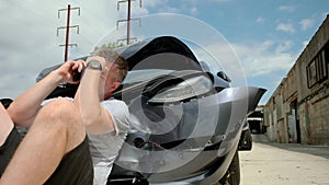 Mature man making a phone call after a car accident, damage car in the background. Close up view