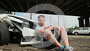 Mature man making a phone call after a car accident, damage white car