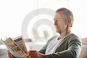 Mature, man and newspaper for reading in home, relax and information or articles in morning with coffee. News, breakfast