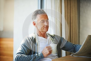 Mature, man and newspaper for reading in home, relax and information or articles in morning with coffee. News, breakfast