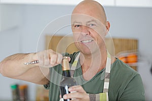 mature man opening bottle red wine