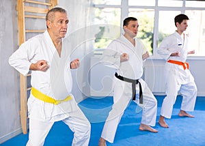 Mature man with other athletes of different ages during karate or judo classes