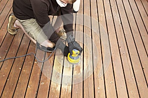 Mature man performing maintenance on home wooden deck