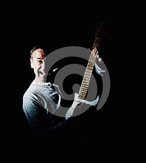 Mature man playing an acoustic guitar against black background. Portrait of a joyful mature man playing an acoustic