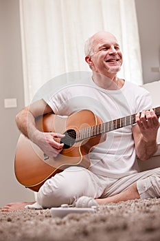 Mature man playing guitar at home