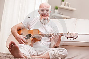 Mature man playing guitar at home