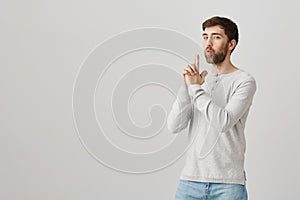 Mature man plays with kids and acts like soldier. Studio shot of childish father showing weapon or gun gesture, blowing
