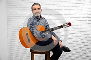 Mature man posing in studio with guitar.