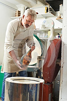 Mature Man In Pottery Studio Firing Vase In Kiln