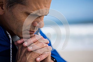 Mature man praying with hands clasped