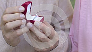 Mature man presenting precious engagement ring with diamond to woman, close up