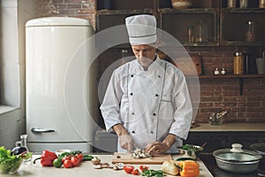 Mature man professional chef cooking meal indoors