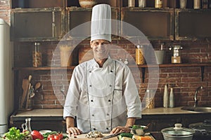 Mature man professional chef cooking meal indoors