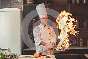 Mature man professional chef cooking meal indoors