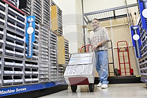 Mature man pushing handtruck in hardware store