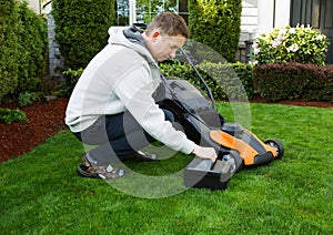 Mature man putting battery into electric Lawn Mower