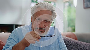 Mature man putting on eyeglasses. Serious older man looking at camera