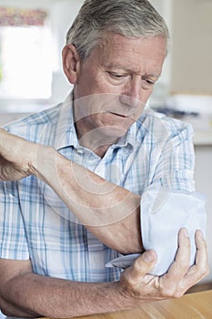 Mature Man Putting Ice Pack On Painful Elbow