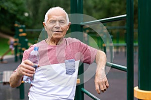 Mature man quenches her thirst from bottle after jogging in park