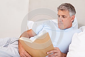 Mature man reading book in bed