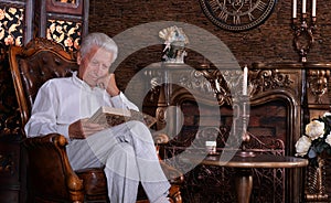 Mature man reading book at room with vintage interior