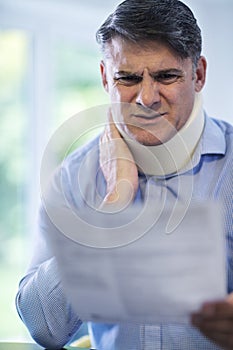 Mature Man Reading Letter After Receiving Neck Injury