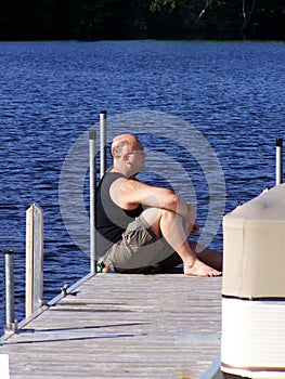 Mature man relaxing on a dock by the water