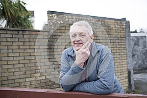 Mature man resting on a wooden gate outdoors