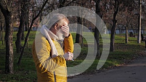 Mature man rubbing his eyes because he feels some itchiness due to allergy or infection while walking in city park