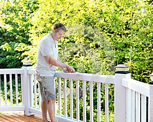 Mature man scraping old paint from outdoor deck