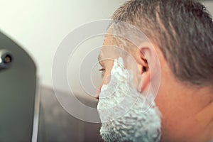 Mature man shaving in front of mirror
