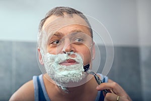 Mature man shaving in front of mirror