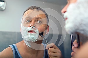 Mature man shaving in front of mirror