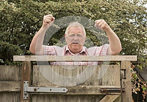 Mature man shouting and shaking his fists over a fence