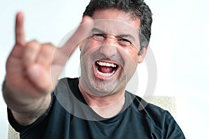 Mature man showing the devil thorns gesture sign