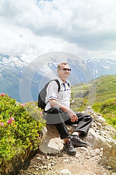 Mature man sits on top of a mountain