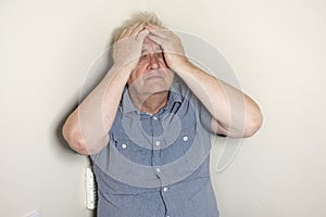 Mature man sitting in the corner of the room looking worried