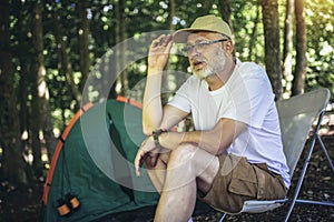 Mature man sitting in the forest with a tent in background. Mature man sitting at a campsite