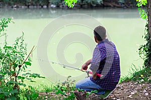 Mature man sitting on the river bank and fishing, summer outdoor. Sesonal leisure. Fishing. Angling
