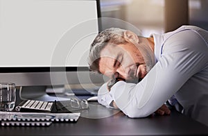 Mature man, sleeping and tired in office with computer, desk and exhausted as employee with deadline. Company, business