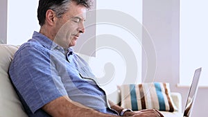 Mature man on the sofa typing on his laptop