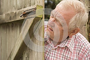 Mature man spying round a wooden door