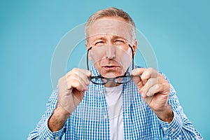 Mature man squinting wearing eyeglasses, looking at camera