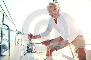 Mature man standing on his boat using a winch