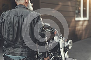 Mature man standing near motorbike