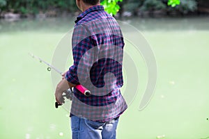 Mature man standing on the river bank and fishing, summer outdoor. Sesonal leisure. Fishing. Angling